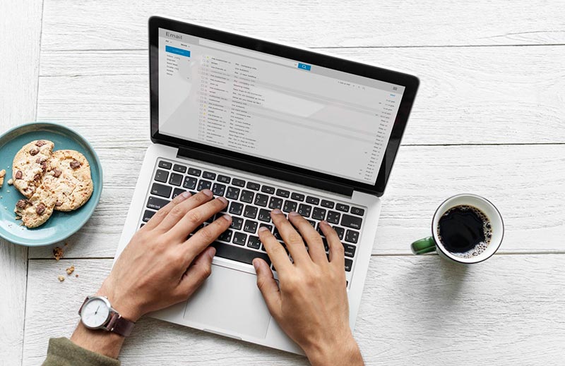 Male hands typing in an email on a laptop computer