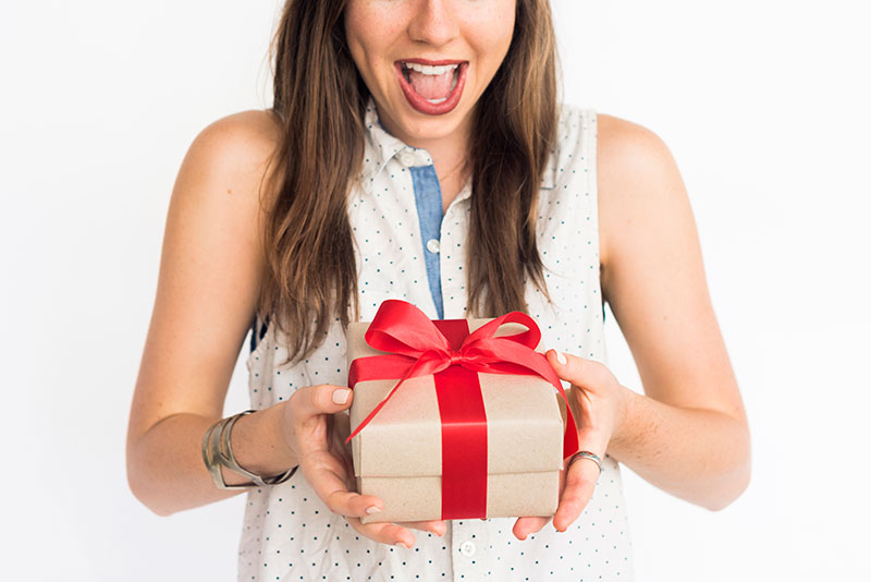 Very excited lady holding a wrapped present with a red bow